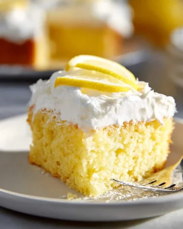 Deliciously moist lemon poke cake topped with lemon glaze and fresh berries.