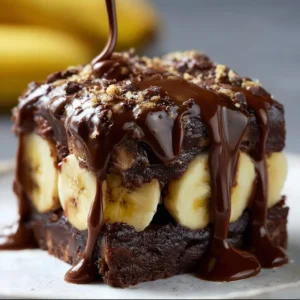 Delicious chocolate covered banana brownies on a plate topped with nuts