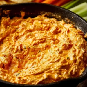 Bowl of creamy Buffalo Chicken Dip with crispy chips and fresh celery on the side.