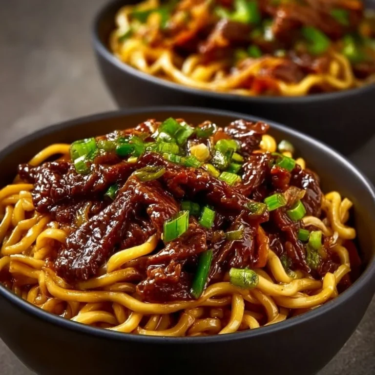 A bowl of sticky beef noodles topped with fresh herbs and spices.