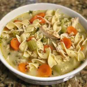 Creamy chicken noodle soup in a white bowl garnished with parsley