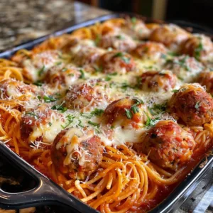 Delicious meatball spaghetti bake topped with cheese and herbs