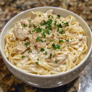 Crockpot Chicken Alfredo served with fettuccine and garnished with parsley.