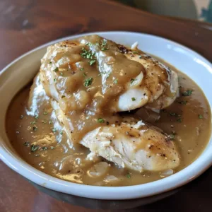 Crockpot chicken cooked with rich onion gravy served on a plate.